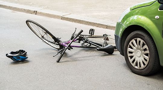 A green car that hit a pink bicycle