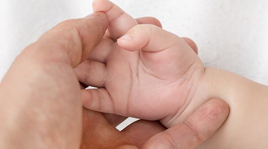 Parent holding baby's hand