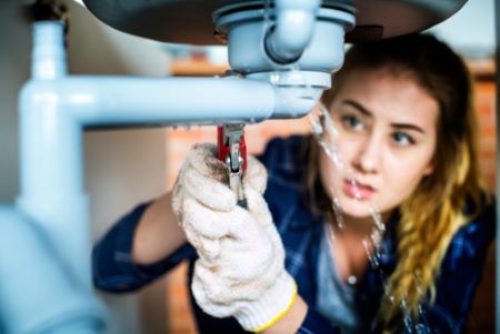 A women fixing a leak under a sink